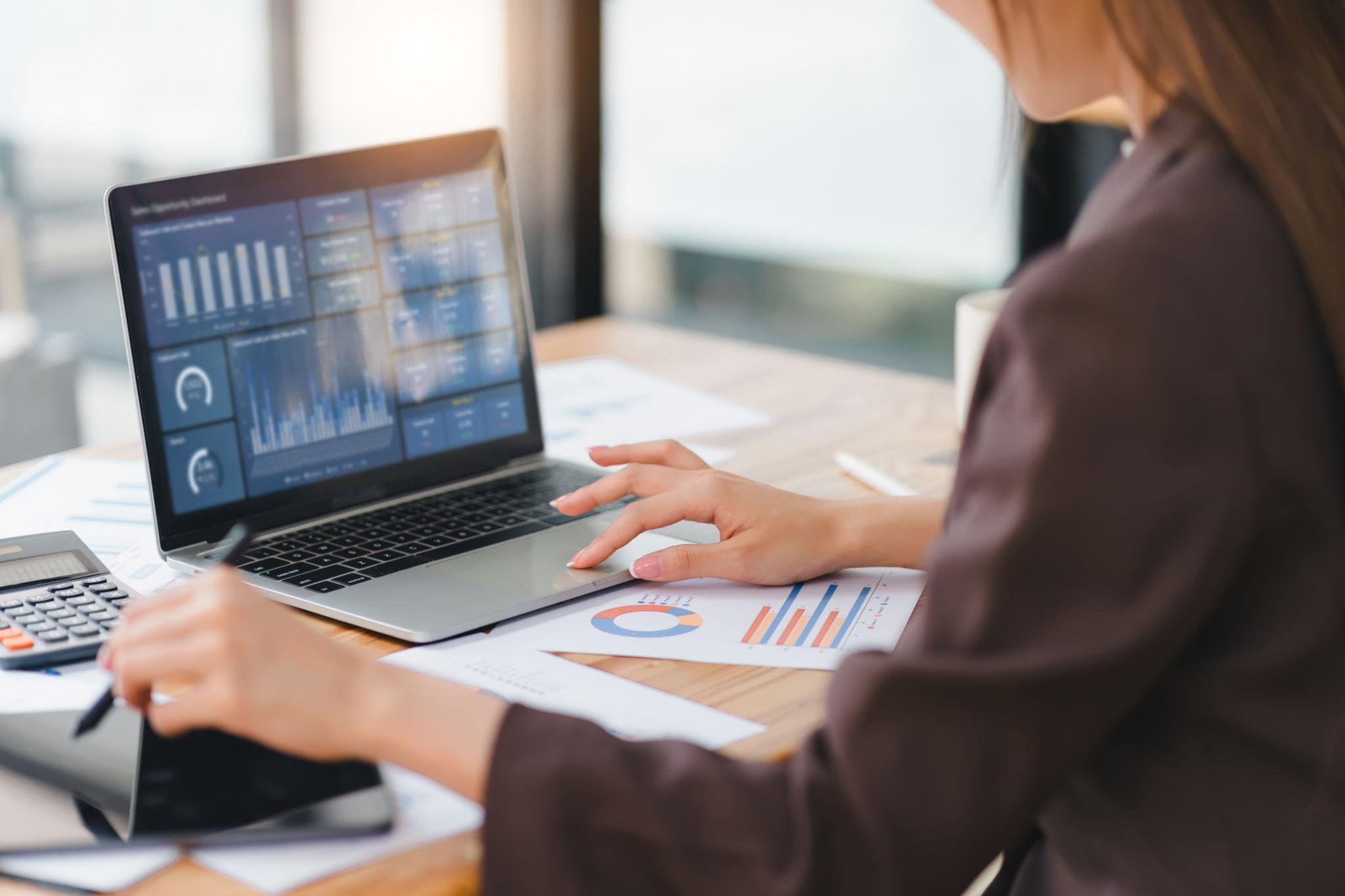 Healthcare professional analyzing business data and financial reports on a laptop